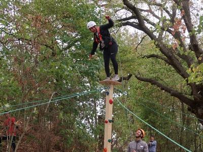 Mit Hilfe ihres Teams erklimmt eine Person den Balken.
