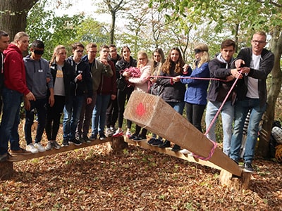 Eine Gruppe baut mit Holzbalken eine Brücke.